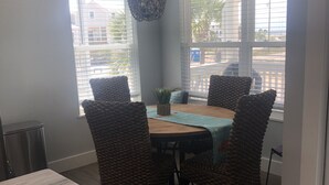 A dining area with a wooden table, four woven chairs, and a hanging light fixture.