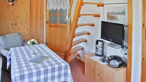 A bedroom with a bed, a desk with a computer, a TV, and a wooden ladder. - Ferienhaus Lassan bei Wolgast (Lassan bei Wolgast)