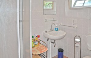 A bathroom with a sink, mirror, and window.