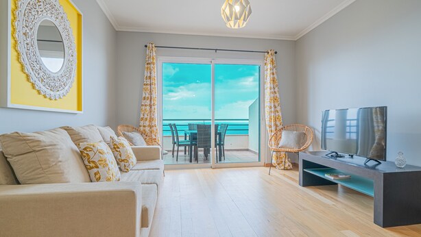 Una sala de estar moderna con un sofá, televisor y un balcón con vistas.