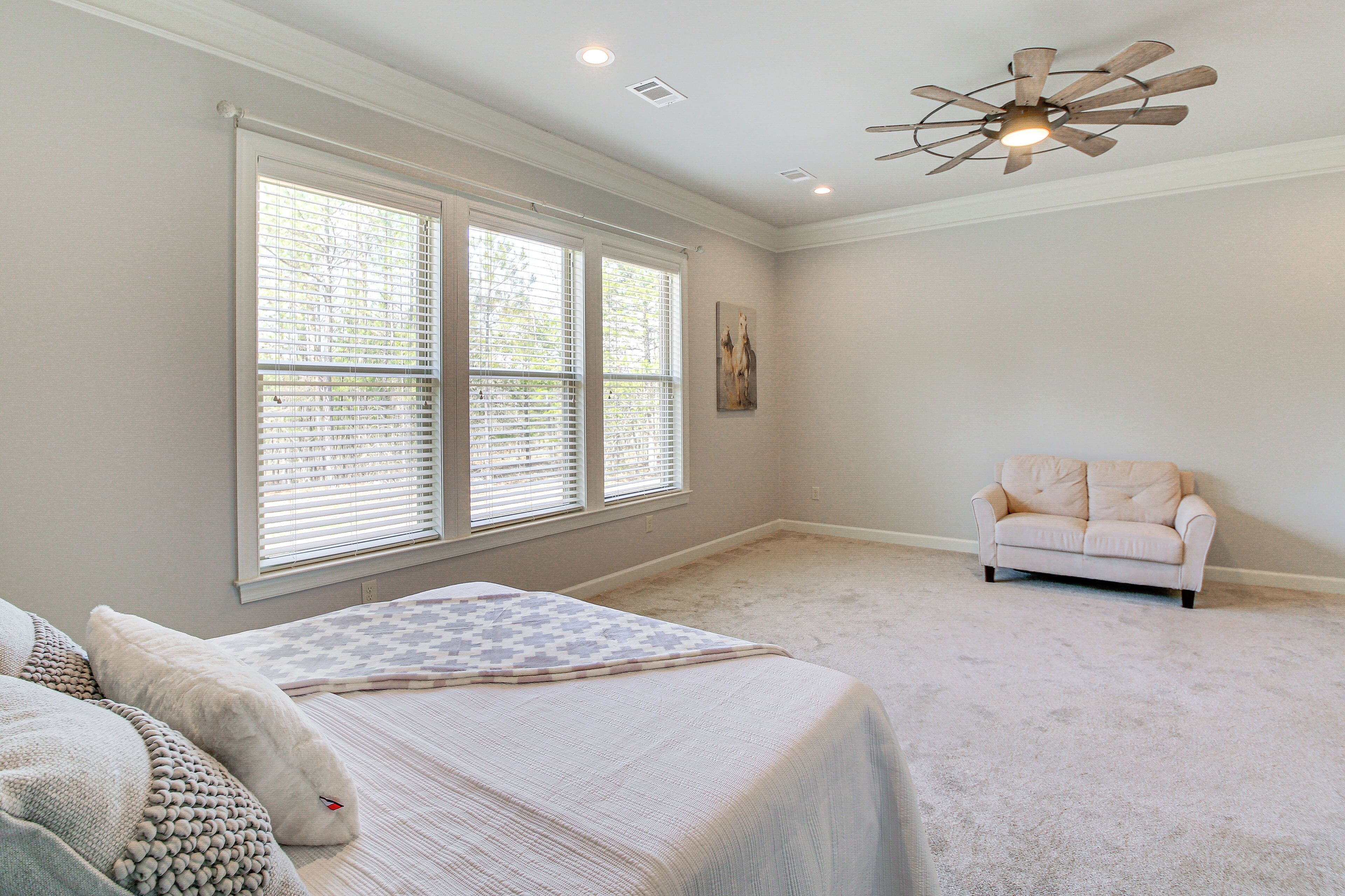 A bedroom with a large window, a ceiling fan, and a white sofa.