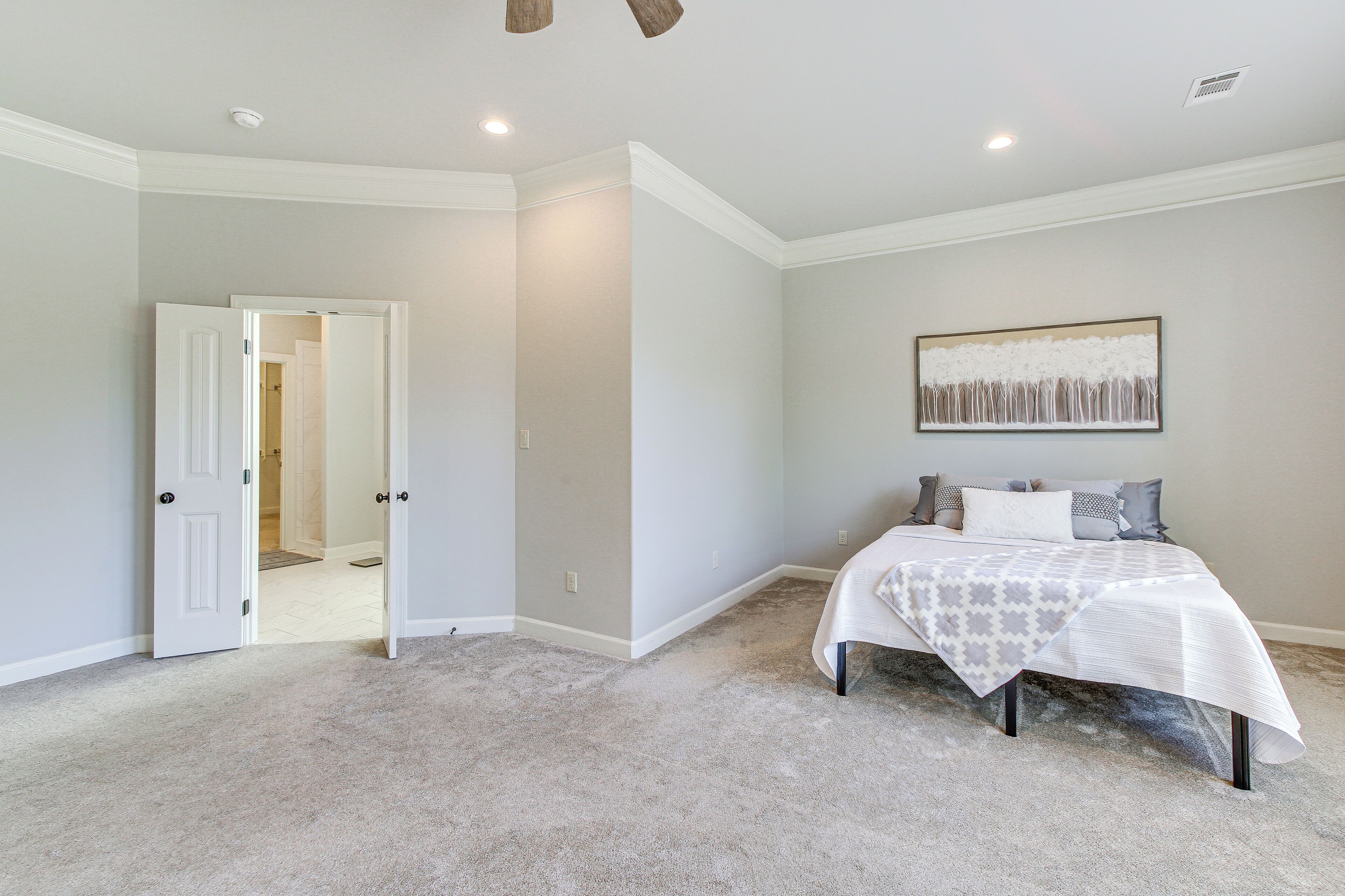 Un dormitorio con cama, una puerta que da a otra habitación y una lámpara en el techo.