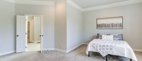Un dormitorio con cama, una puerta que da a otra habitación y una lámpara en el techo.