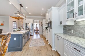 A modern kitchen with white cabinetry, a granite countertop, and a central island. - Spacious Hot Springs Village Home < 1 Mi to Lake! (Hot Springs Village)