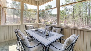 A covered patio with a table and chairs, large windows, and a view of trees and houses. - Spacious Hot Springs Village Home < 1 Mi to Lake! (Hot Springs Village)