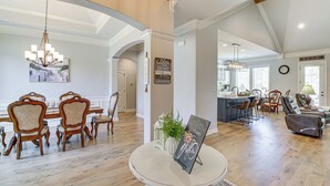 A spacious living room with a round table, a chandelier, and a dining area with wooden chairs. - Spacious Hot Springs Village Home < 1 Mi to Lake! (Hot Springs Village)