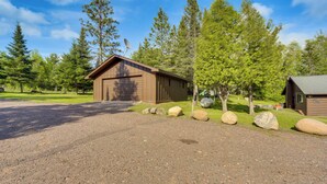 A cabin with a gravel driveway, large rocks, and a garage. - Hayward Retreat on the Chippewa Flowage w/ Dock! (Hayward)