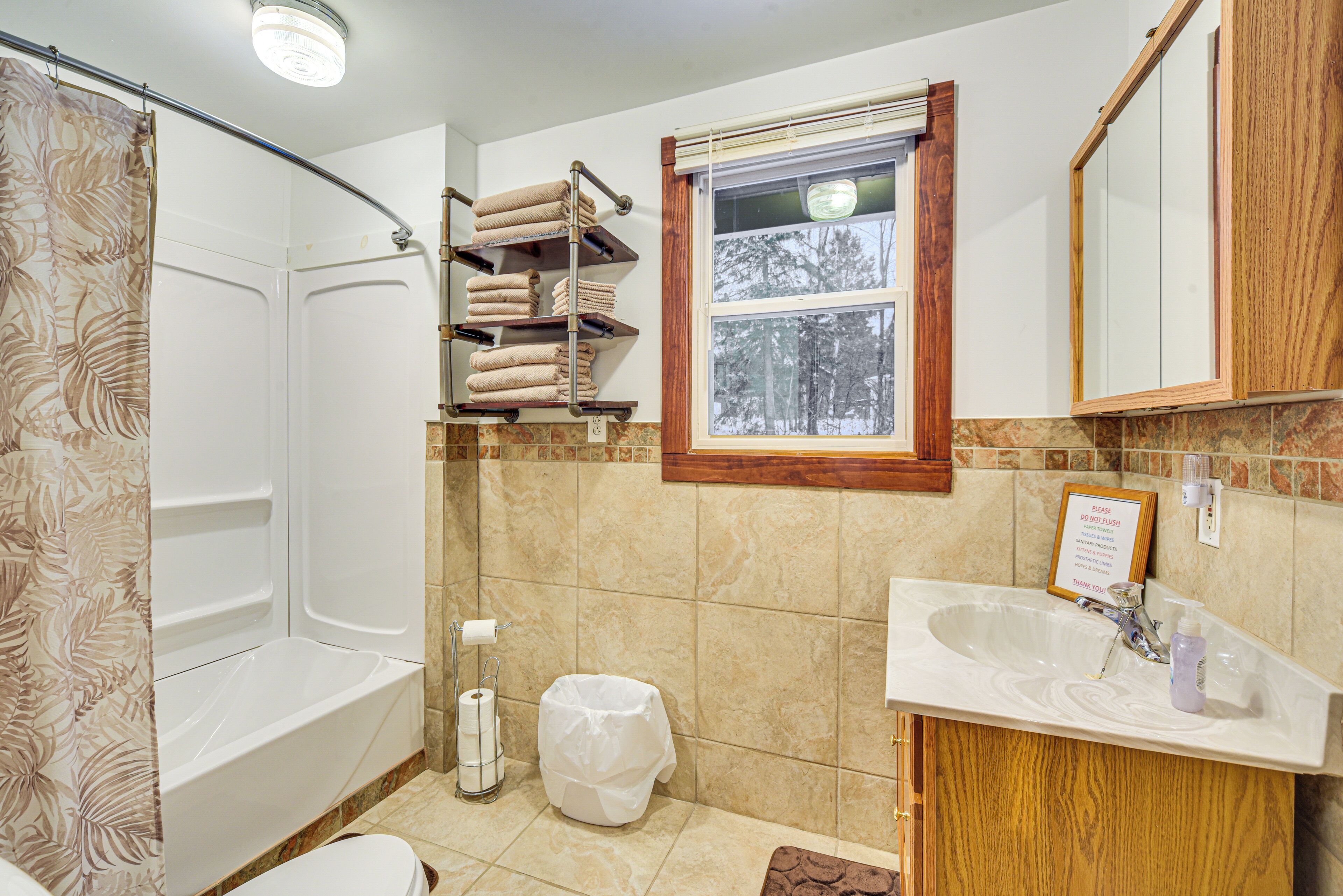 A bathroom with a bathtub, a sink, a window, and a towel rack.