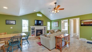 A spacious living room with a fireplace, a ceiling fan, and a television. - Angola Getaway: Walk to Lake Erie Beach Park! (Angola)