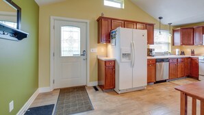 A kitchen with wooden cabinets, a refrigerator, and a window with blinds. - Angola Getaway: Walk to Lake Erie Beach Park! (Angola)