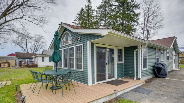 A single-story house with a covered patio, a sliding glass door, and a green umbrella. - Angola Getaway: Walk to Lake Erie Beach Park! (Angola)