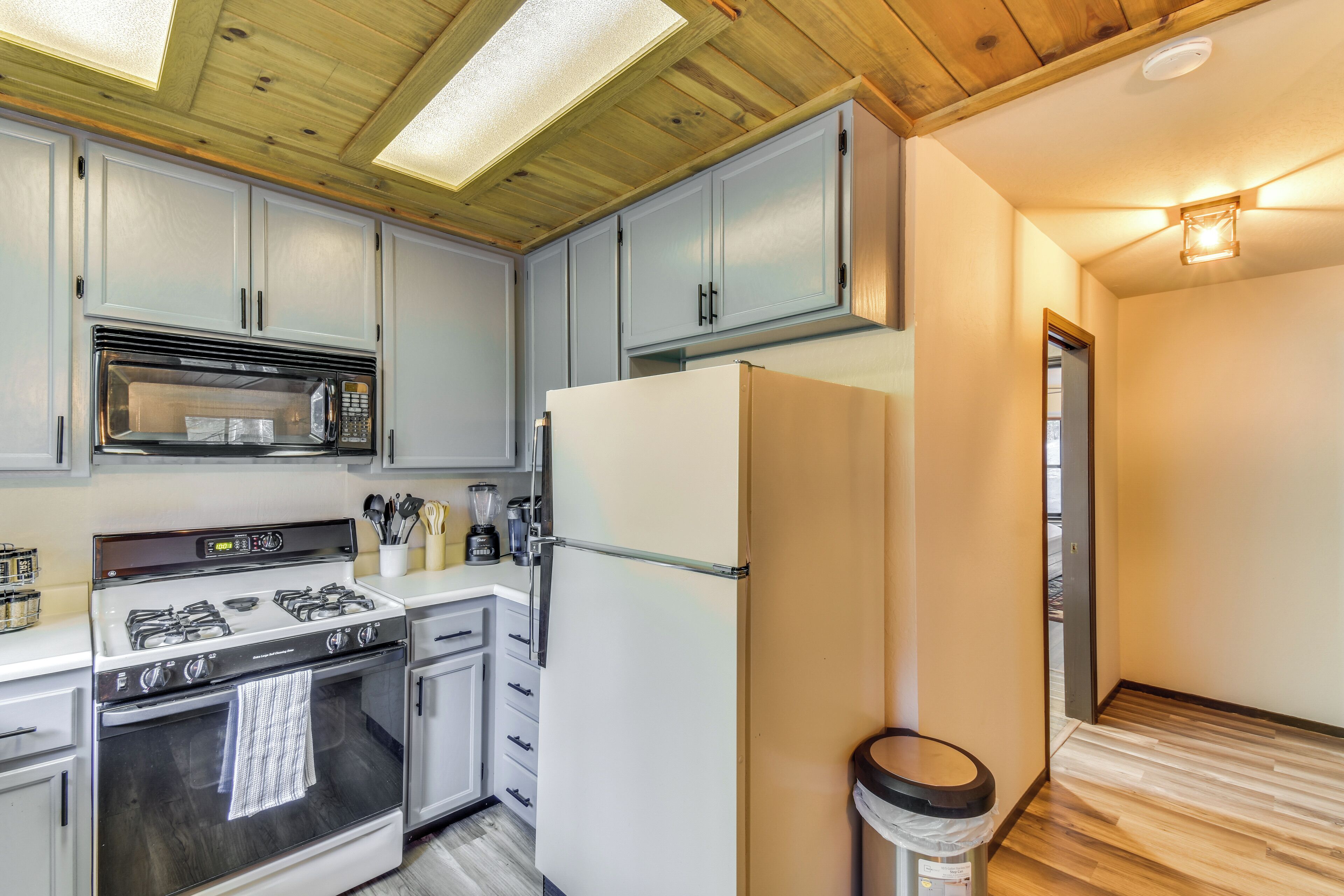A modern kitchen with white cabinets, a stainless steel stove, a microwave, and a refrigerator.