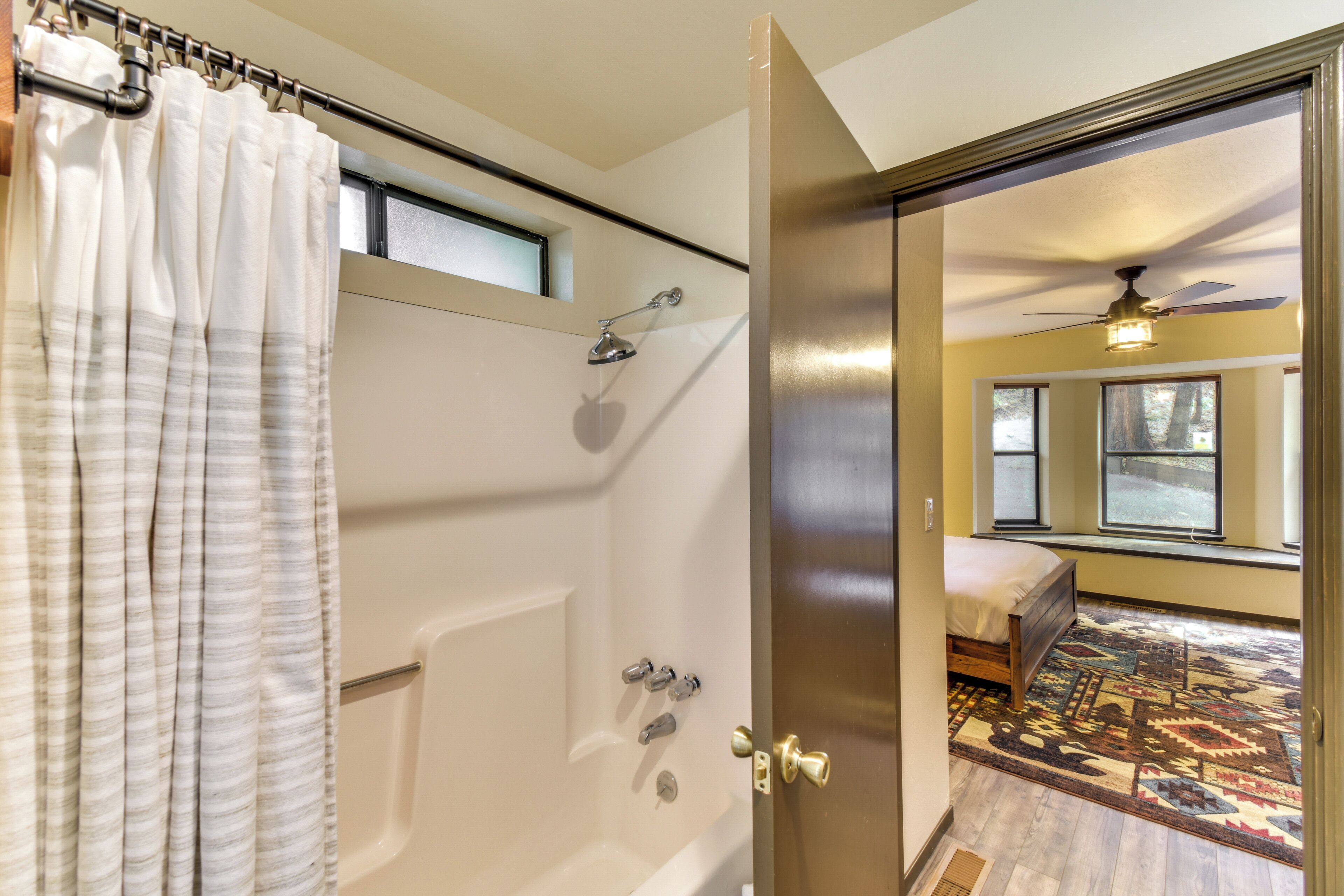 Un baño con bañera, ducha y una ventana sobre la bañera.
