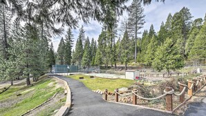A paved pathway curving through a park with a grassy area, wooden fence posts, and a building in the background. - Game Room + Pool Access: Spacious Cabin in Arnold (Arnold)