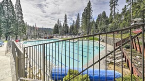 A swimming pool surrounded by tall trees, with a wooden deck and a metal railing. - Game Room + Pool Access: Spacious Cabin in Arnold (Arnold)
