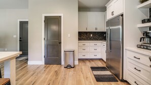 A modern kitchen with white cabinetry, a stainless steel refrigerator, and a herringbone tile backsplash. - Game Room + Pool Access: Spacious Cabin in Arnold (Arnold)