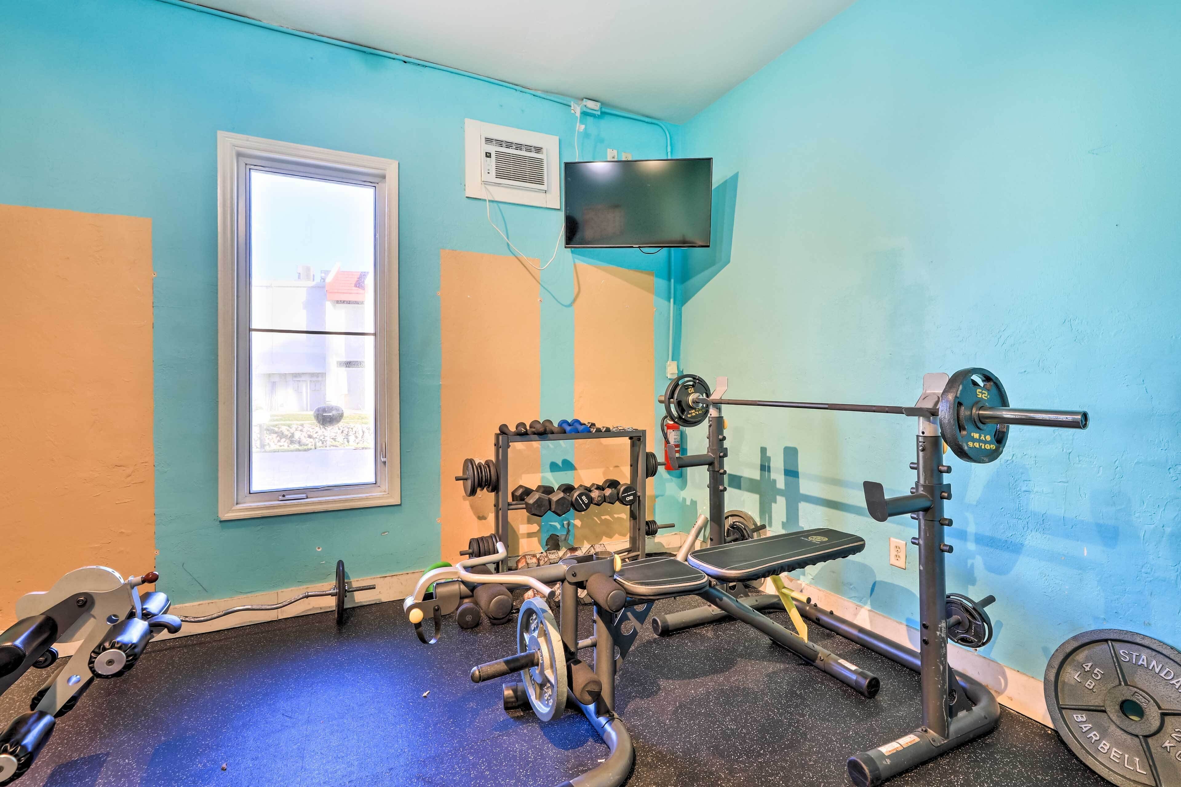 A gym with exercise equipment, a window, and a television mounted on the wall.