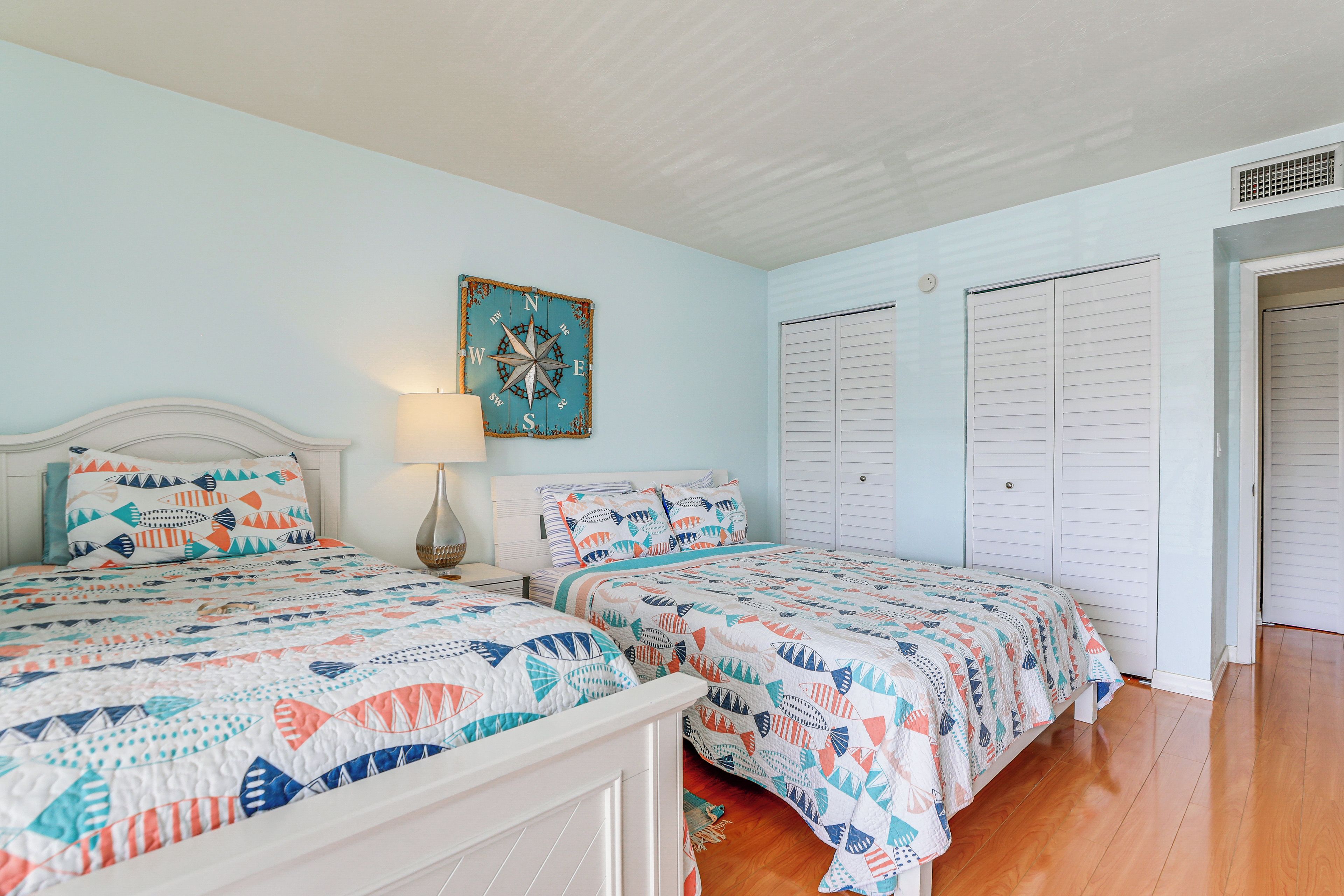 A bedroom with two beds, a wall-mounted compass decoration, and a white headboard.