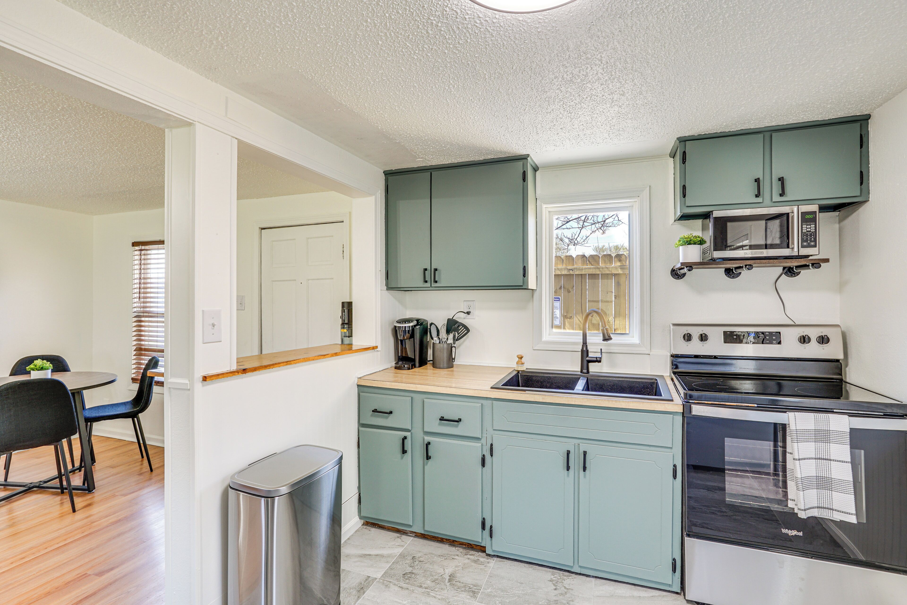 A compact kitchen with teal cabinets, a microwave, and a stove.