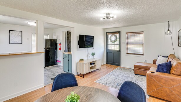 A modern living room with a dining area, a kitchen, and a door leading to the outside. - Jefferson City Bungalow: Hot Tub & Patio! (Jefferson City)