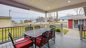 A covered outdoor patio with a metal table and chairs, a view of the street, and a small shed in the background. - Angola Vacation Rental, Walk to Lake Erie Beach! (Angola)