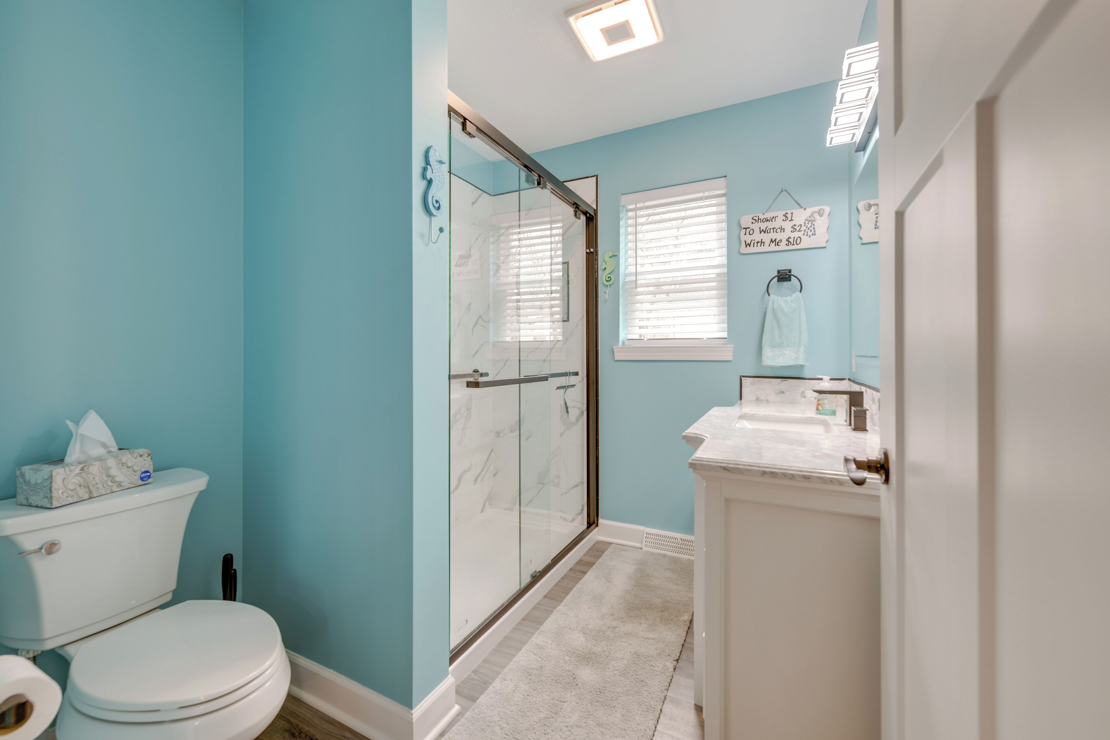 Une salle de bain comprenant des toilettes, une douche à parois de verre, un lavabo et un porte-serviettes.
