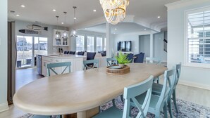 Un vaste espace dédié à la salle à manger, avec une grande table ovale, des chaises bleu clair et un lustre décoratif.