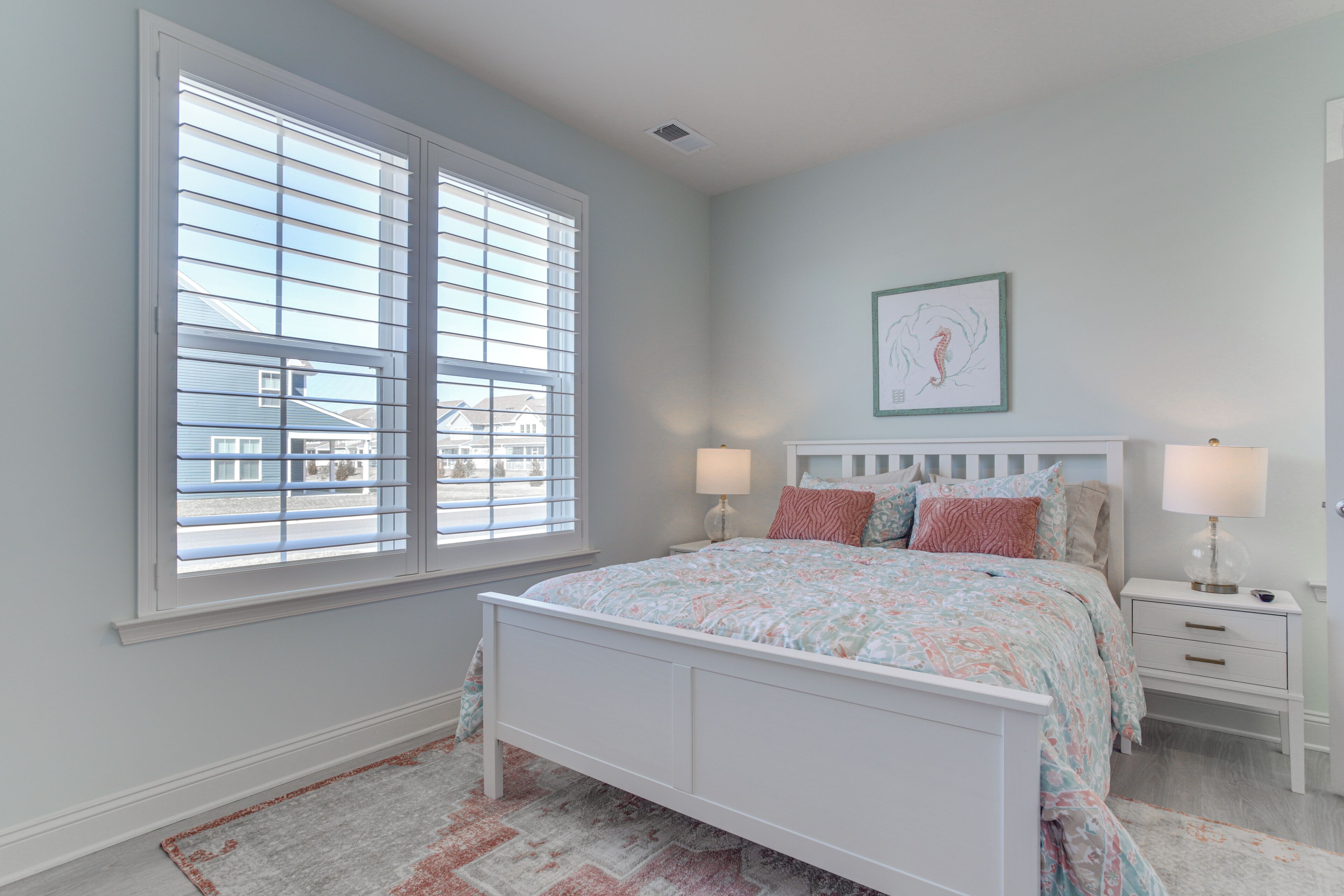 A bedroom with a bed, nightstands, a window with blinds, and a framed picture on the wall.
