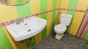 A bathroom with a white sink, a toilet, and a striped tile border. - Hotel O Budi Residence 2 (Bekasi)