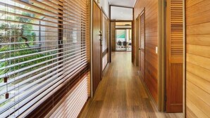 A hallway with wooden walls and blinds, leading to a room with a view of greenery. - Beach Access Home with Private Outdoor Retreat (Cowes)