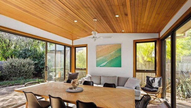 A modern dining area with a wooden table, chairs, and a sofa. - Beach Access Home with Private Outdoor Retreat (Cowes)