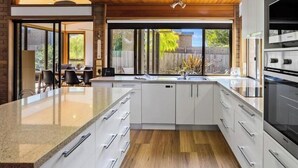 A modern kitchen with a large island, white cabinetry, and a wooden ceiling. - Beach Access Home with Private Outdoor Retreat (Cowes)
