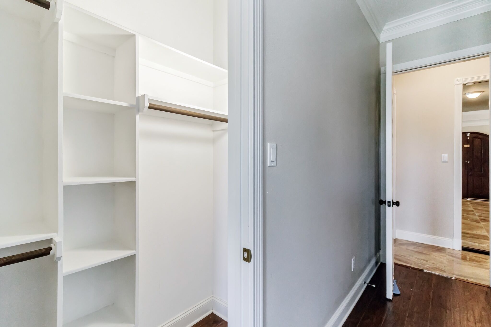 A hallway with a white closet and a door leading to another room.