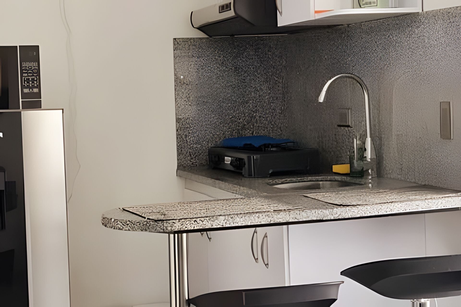 A kitchen with a granite countertop, stainless steel sink, and modern cabinetry.