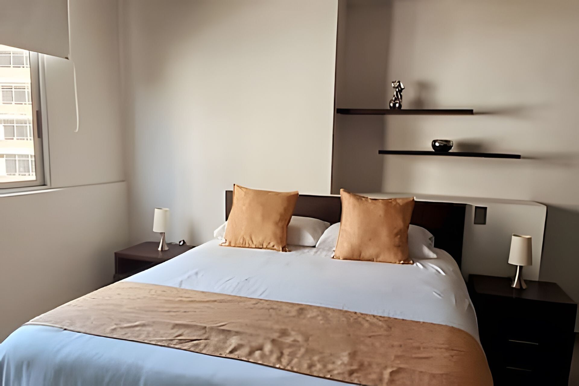 Ein ordentlich eingerichtetes Hotelzimmer mit einem Bett, zwei Nachttischen und einem Fenster.