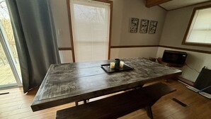 A dining area with a wooden table, benches, and a television. - The Bungalow on Lake Navajo (Cherokee Village)