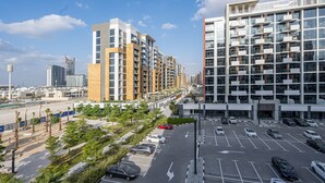 A modern apartment complex with multiple high-rise buildings, a parking lot, and a beachside promenade. - Comfy 1BR Apartment in Azizi Riviera 8, Al Merkadh by Deluxe Holiday Homes (Dubai)