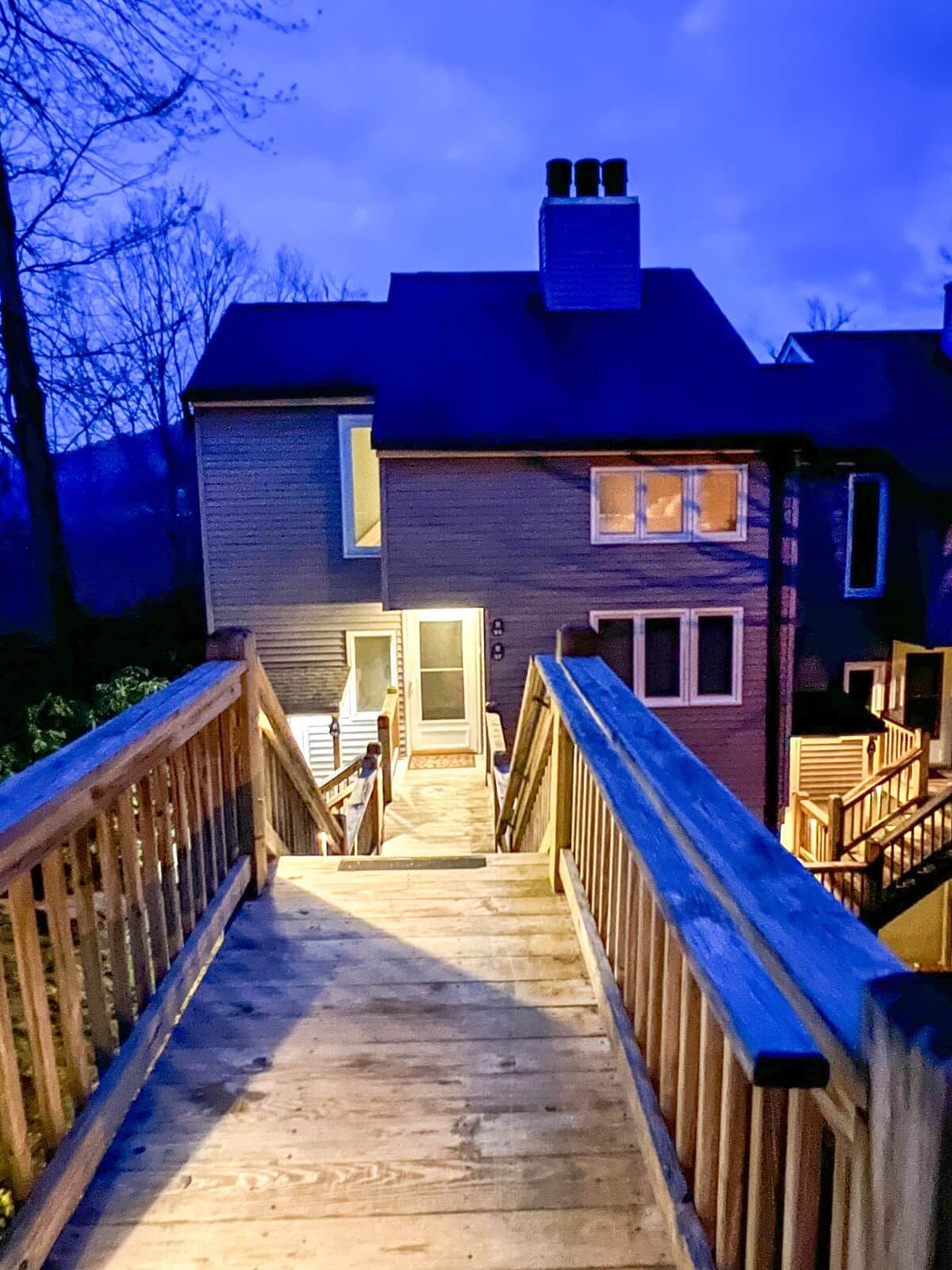A wooden staircase leading to a residential building with a visible door and windows.