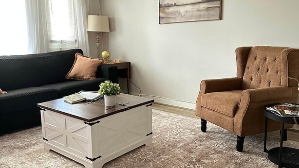 A living room with a sofa, armchair, coffee table, lamp, globe, and a painting on the wall. - Cozy Mountain Retreat w/ Balcony Views & Fireplace (Sugar Mountain)