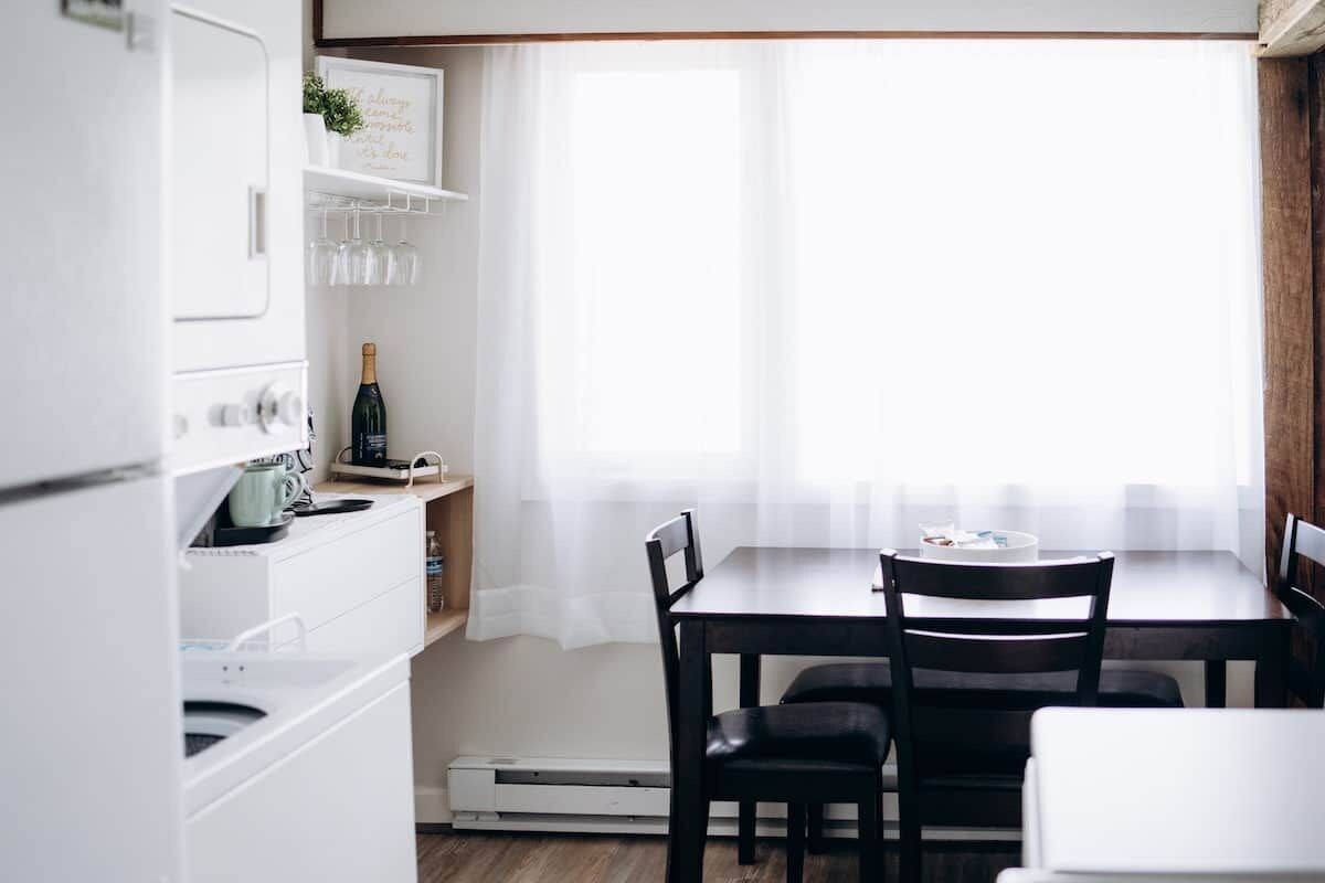 A kitchen with a dining table, chairs, and a bottle of champagne.
