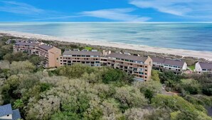 A coastal hotel with multiple buildings, a beach in the background, and surrounding greenery. - 1164 Beach Walker - Adorable oceanfront, just steps to the beach and pool! (Fernandina Beach)