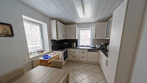 Une cuisine compacte avec des meubles blancs, un plan de travail noir et une petite table à manger.