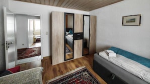 Une chambre moderne avec un plafond en bois, une grande armoire aux portes miroir, un lit avec un coussin à rayures et un petit tapis.