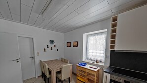 Une cuisine compacte comprenant une table à manger, des chaises, une petite fenêtre et un four encastré.