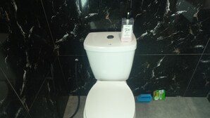 Un bagno con parete in marmo e una boccetta di sapone sul serbatoio.