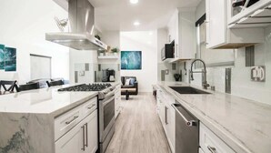 A modern kitchen with white cabinetry, stainless steel appliances, and a marble countertop. - 122 36th St B | Gorgeous + Modern Oasis. Steps to the Beach (Newport Beach)