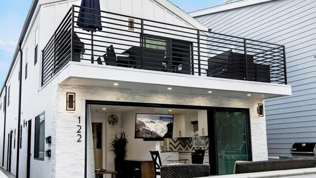 A modern two-story house with a balcony, a garage, and a large window. - 122 36th St B | Gorgeous + Modern Oasis. Steps to the Beach (Newport Beach)