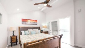 A bedroom with a wooden bed, two bedside tables, a ceiling fan, and a large window. - 122 36th St B | Gorgeous + Modern Oasis. Steps to the Beach (Newport Beach)