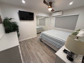 A modern bedroom with a bed, bedside table, lamp, and a ceiling fan. - 122 36th St A | Gorgeous + Modern Oasis w/ Huge Front Patio (Newport Beach)
