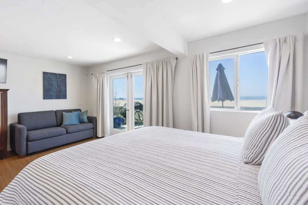 A hotel room with a large bed, a sofa, and a view of the beach.